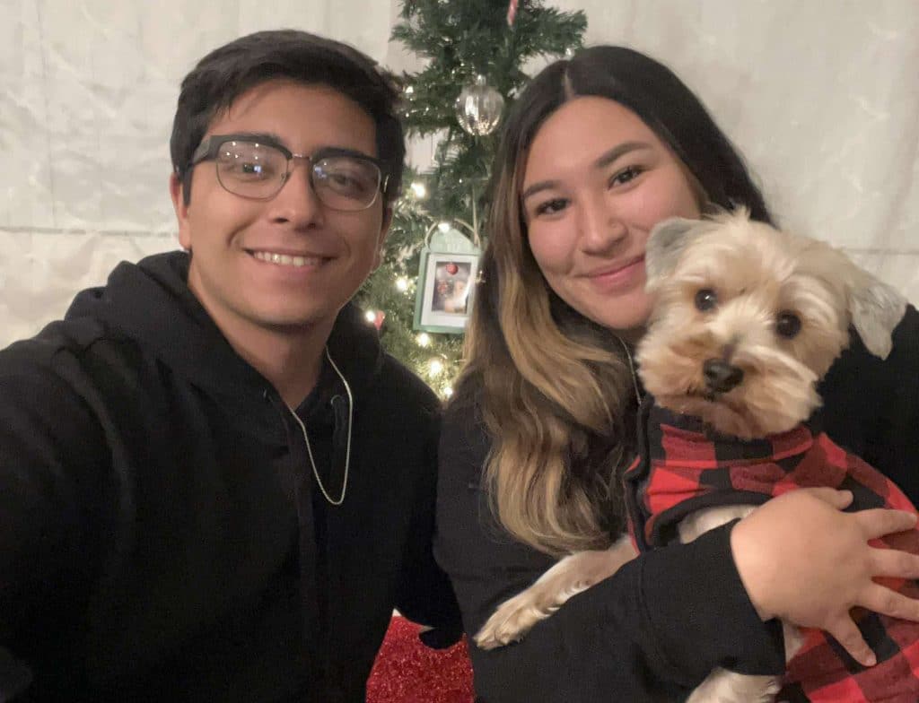Valentin Gamez with a woman holding a dog in front of a Christmas tree