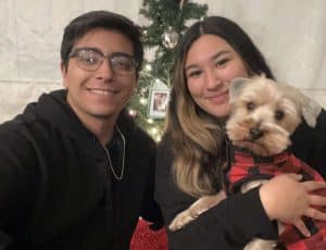 Valentin Gamez with a woman holding a dog in front of a Christmas tree