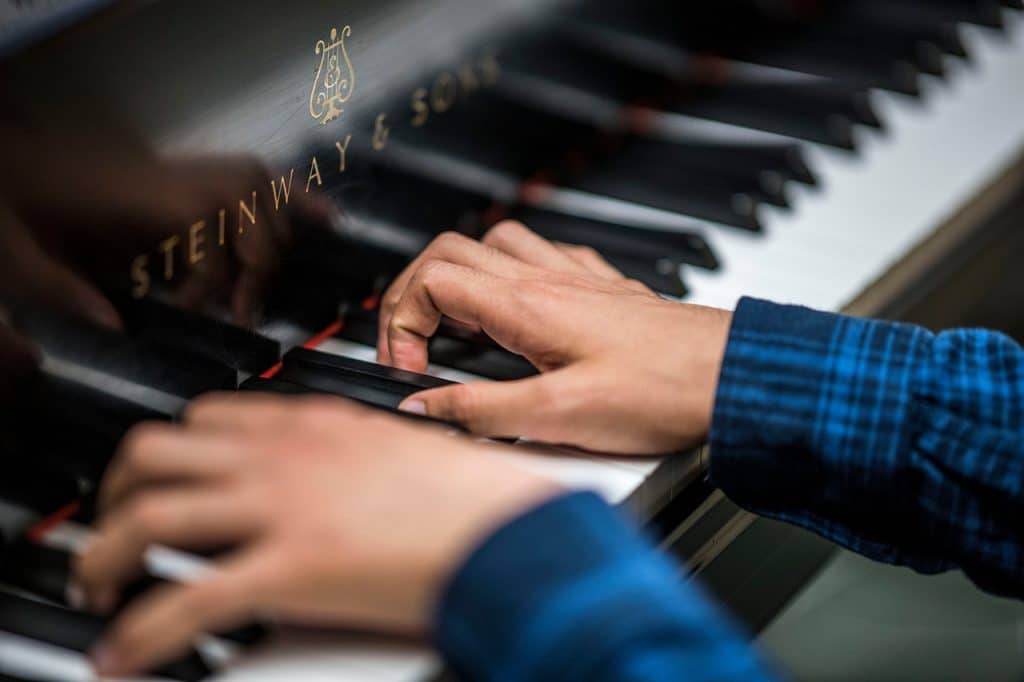 Close up of hands playing Steinway piano