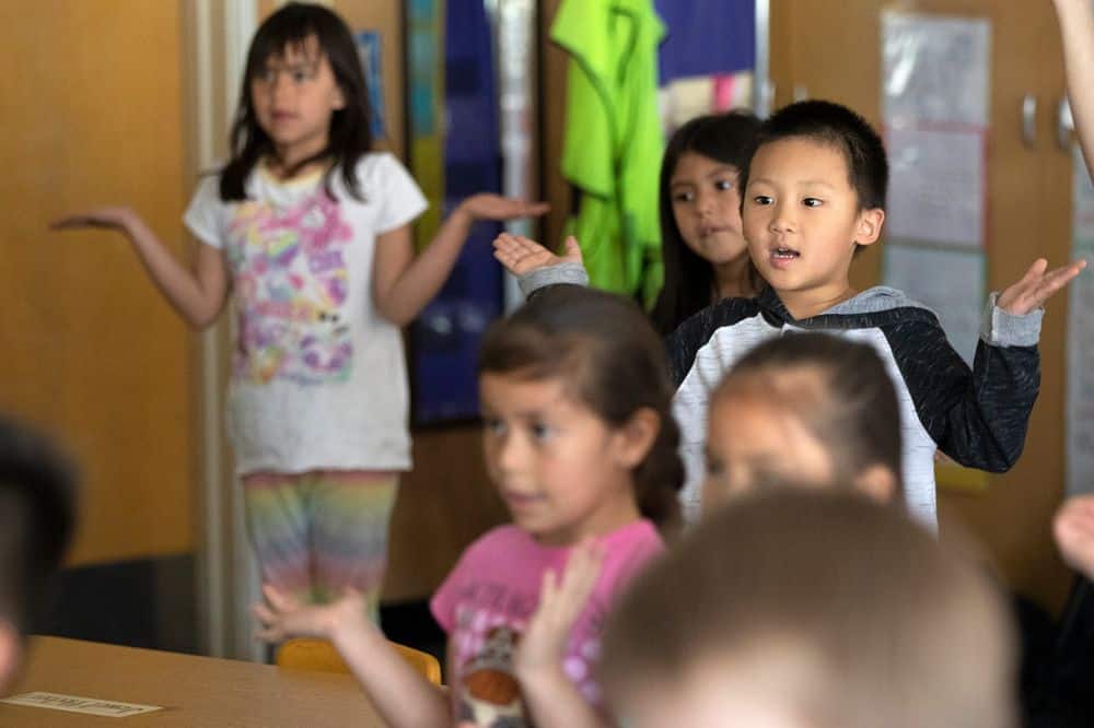 Young students stand with arms out