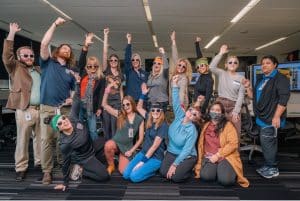 A group of people from the OT department wearing party glasses with hands in the air