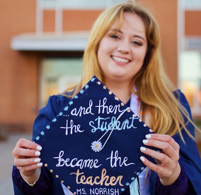 Megan holds up graduation cap