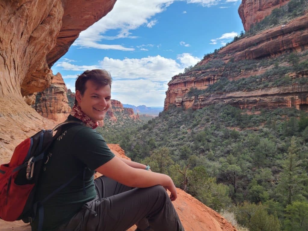 Andrew Svabik sitting on red rocks in Sedona under the blue sky