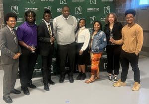 Justin Mallett standing in front of a green background with a number of other adults