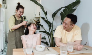 Happy family of three sitting by their dinning room table.