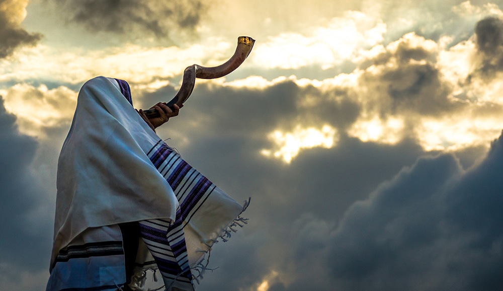 Jewish man in a tallith prayer shawl against dramatic sky