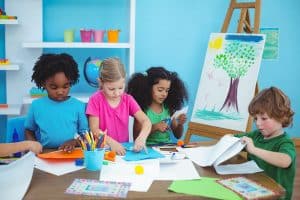 Several young children paint and cut out shapes as they make art.