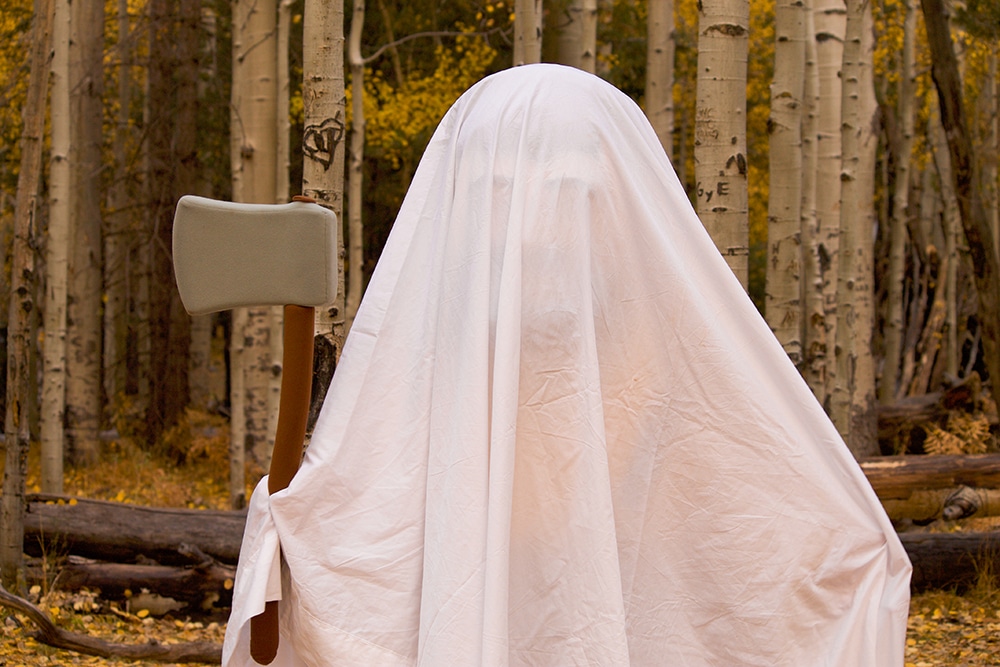 Louie the Lumberjack wearing a sheet like a ghost and holding an axe.