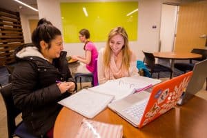 Two students sit at a table with laptops at the Academic Success Center.
