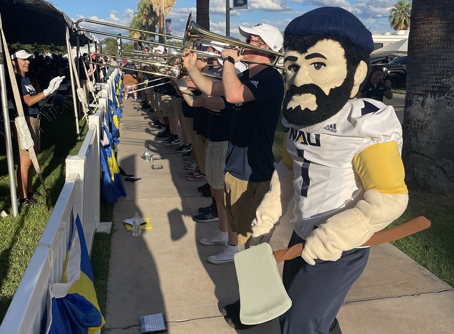 Louie the Lumberjack standing with trombone players by a palm tree