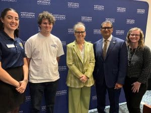 Maria Emilia Machelor, Eli Bergstein, Gov. Katie Hobbs, President Cruz Rivera and another woman in front of an NAU backdrop