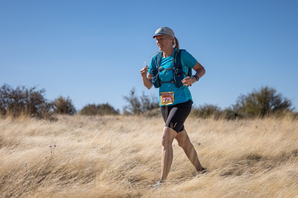 Amy Horn running in an open field with tall yellow grass (photo credit: Howie Stern)