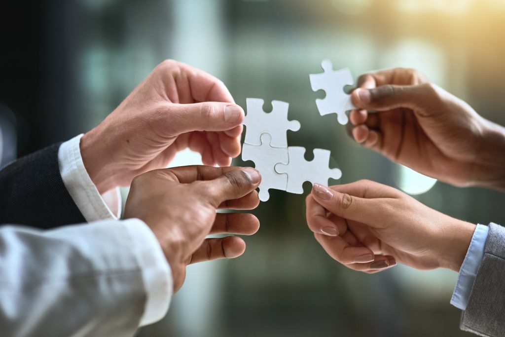 four hands putting puzzle pieces together