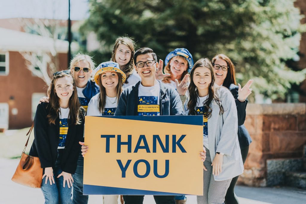 students posing in NAU gear and holding a sign that says Thank You.