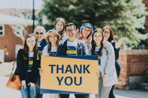 students posing in NAU gear and holding a sign that says Thank You.