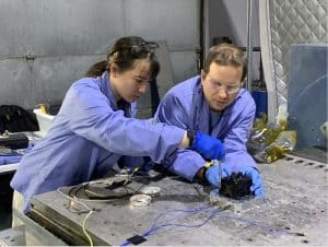 Laura Lee and Christopher Edwards work in a lab wearing PPE.