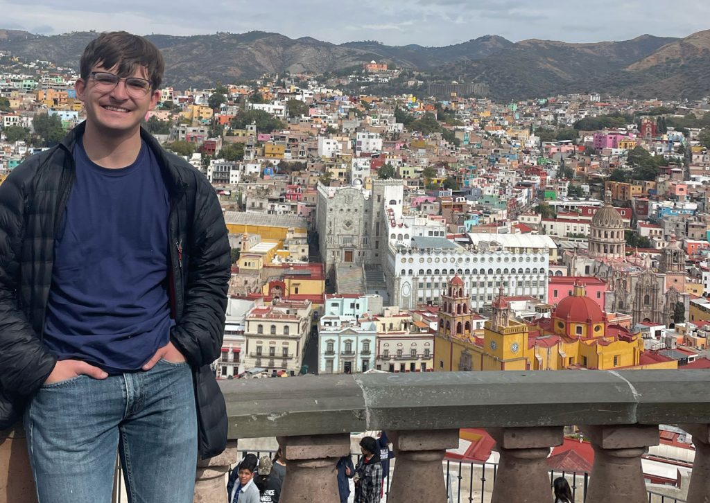 Samuel Conley posing on a balcony overlooking colorful buildings in Queretaro, Mexico