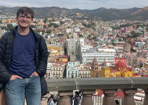 Samuel Conley posing on a balcony overlooking colorful buildings in Queretaro, Mexico