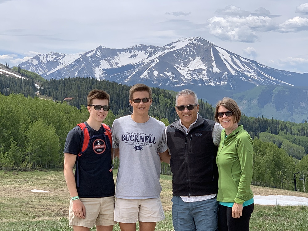 Matthew Ford, his wife and two sons standing in a valley with a snow-covered mountain behind them.