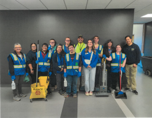 custodial workers posing with special education students, all of whom are wearing blue vests with fluorescent white tape
