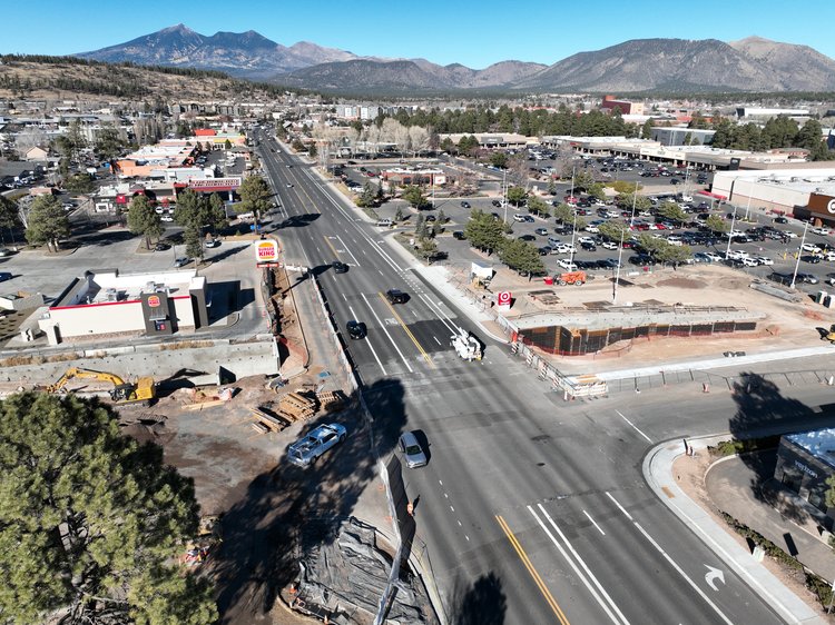 A birds eye view of the intersection of Milton Road and University Drive. Construction vehicles gather in the dirt to the left of Milton Road.