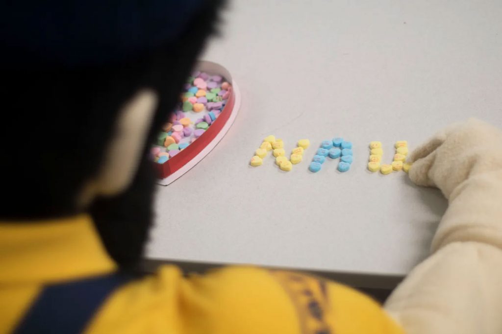 Louie the Lumberjack spelling out NAU with candy conversation hearts
