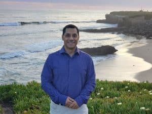 Portrait of Bobby Macias posing in front of a rugged coastline