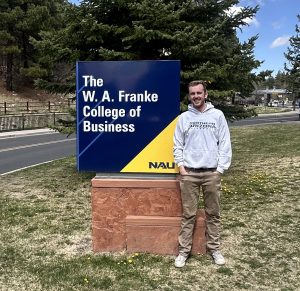 Man in front of Collage of Business sign at NAU