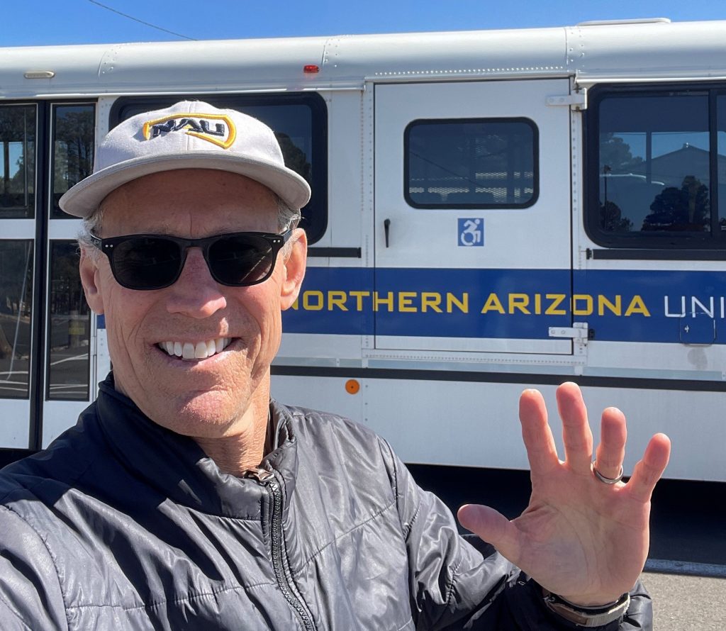 Man standing in front of an NAU shuttle bus