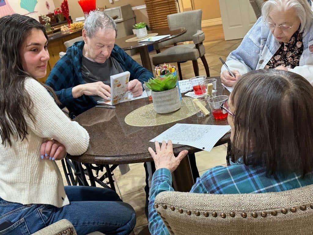 Emma Patterson sitting at a table with seniors at The Peaks writing pen pal letters