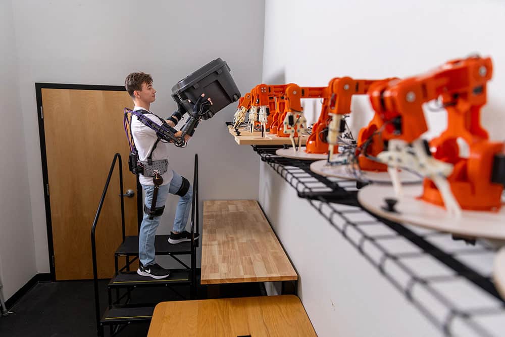 A student demonstrates how a robotic exoskeleton allows for strong movement.