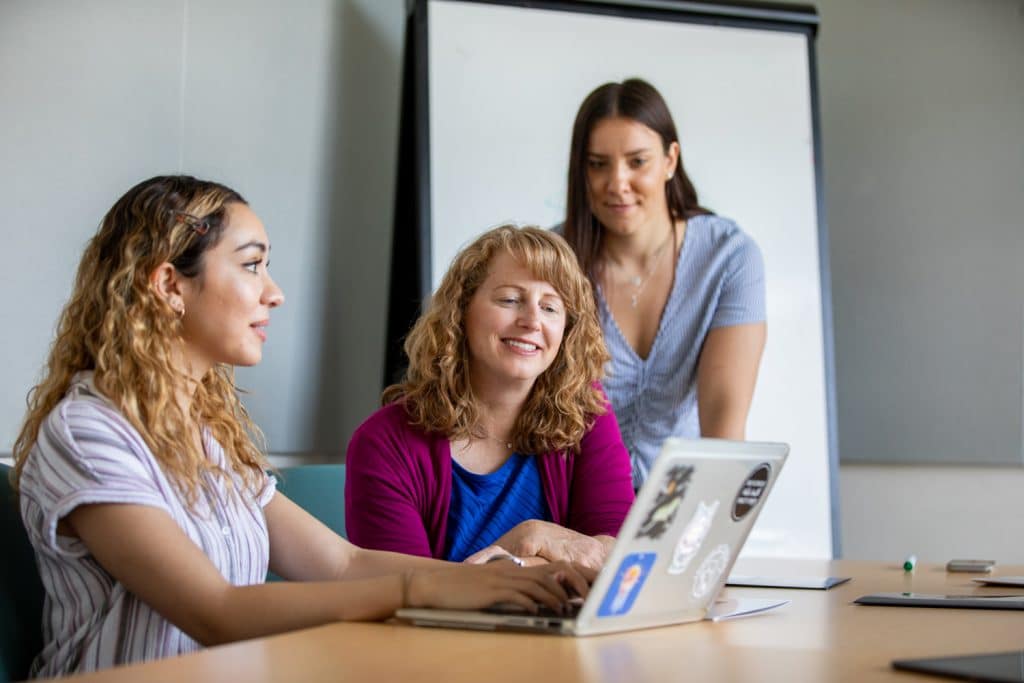 Dawn Clifford looking over a student's shoulder as the student points to something on a laptop