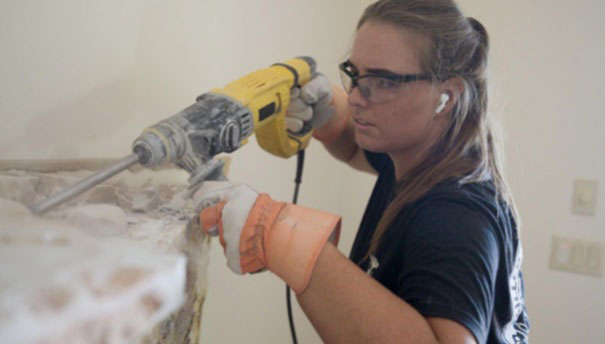 Grace Johnson using a power drill and wearing protective glasses