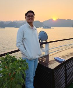 Jackson Truitt standing in front of water and a sunset