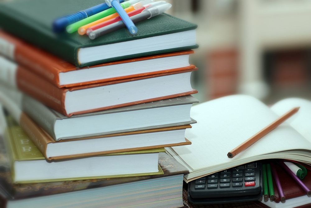 A stack of textbooks with highlighters on top