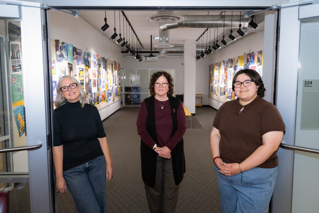 Patricia Murphey, Kathleen M. McGeever and Mia Avelar standing at the entrance of The Long Road Together exhibition at NAU