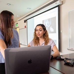 two female students studying in a classroom with laptop