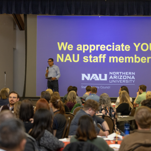 President in front of sign that says we appreciate you NAU staff